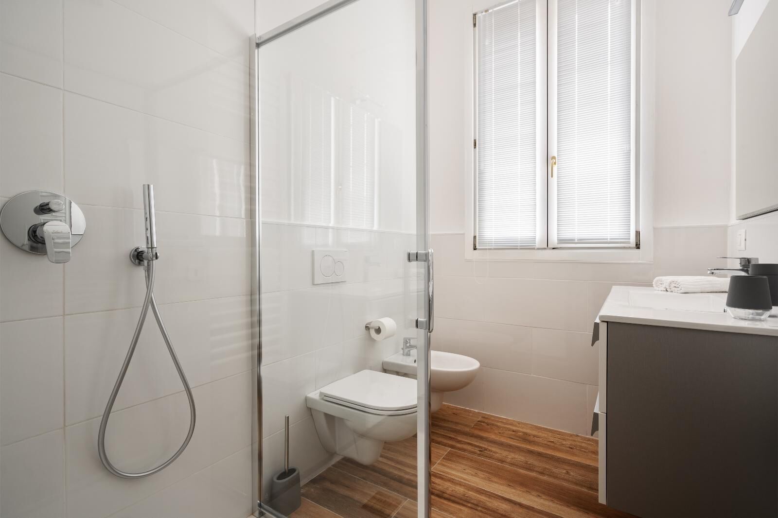 Un bagno moderno con cabina doccia in vetro, un water e un lavandino con specchio.