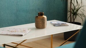 A modern room with a white table, a textured vase, a magazine, and a plant. - Golden Teal apartment (BERGAMO)