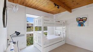 Une chambre avec un lit superposé, une fenêtre, un bureau avec une lampe et un tableau au mur.