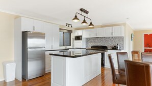 Una cocina moderna con armarios blancos, un refrigerador de acero inoxidable, una isla central y una encimera negra.