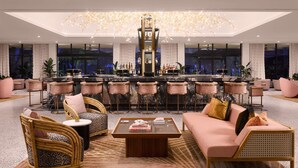 A modern lounge area with a bar, seating arrangements, and a large chandelier.