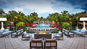 A rooftop pool area with lounge chairs, a fire pit, and a view of the pool.