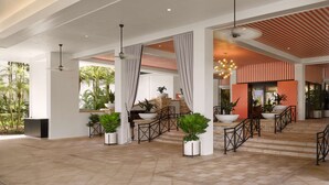 A spacious lobby with a modern design, featuring a staircase, potted plants, and a reception area.