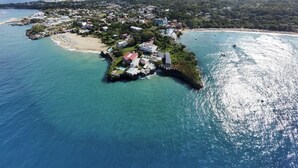 An aerial view of a coastal island with a small settlement, clear blue waters, and a sandy beach. - Beautiful Apartment in Sosua with Maid included (Sosua)