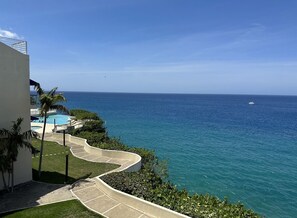 Ett semesterhotell med en pool, en slingrande gångväg och utsikt över havet.