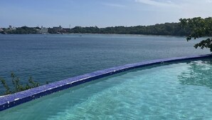 A clear blue sky, a calm sea, and a pool with a tiled edge. - Beautiful Apartment in Sosua with Maid included (Sosua)