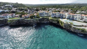 A coastal hotel with multiple buildings, a rocky shoreline, and clear blue waters. - Beautiful Apartment in Sosua with Maid included (Sosua)