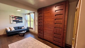 Un salon comprenant un canapé, une table basse, un tapis et une grande armoire en bois.