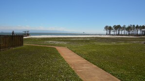 A grassy area with a concrete path leading to a beach. - Labor Day is open! SURFS UP! Family friendly. Finance with Affirm! (Dauphin Island)