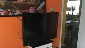 A flat-screen TV on a white entertainment unit in a room with orange walls. - FALL RATES!  SURFS UP! Family friendly. Finance with Affirm! (Dauphin Island)
