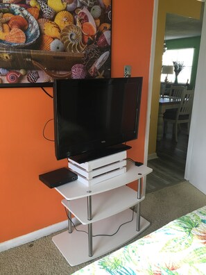 A flat-screen TV on a white entertainment unit in a room with orange walls. - FALL RATES!  SURFS UP! Family friendly. Finance with Affirm! (Dauphin Island)