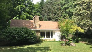 A house with a brick chimney, white siding, and a front porch. - Country Home, outdoor spaces, secluded but close to everything (Traverse City)