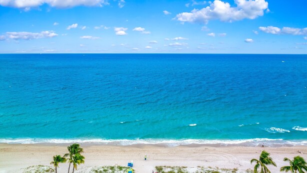 A beach with clear blue water, palm trees, and a sandy shore. - Heated Pool+Hot Tub+Walk To Beach/Shops+Mini Golf! (Lauderdale-by-the-Sea)