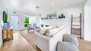 A modern living room with a white fireplace, a sofa, and a coffee table. - Heated Pool+Hot Tub+Walk To Beach/Shops+Mini Golf! (Lauderdale-by-the-Sea)