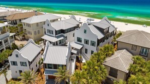 A coastal hotel with multiple buildings, a beach view, and palm trees. - Foresight: Stunning Gulf Front Home, Private Pool w/ Spa, Guest House (Panama City Beach)