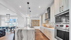 A modern kitchen with marble countertops, stainless steel appliances, and a central island. - Foresight: Stunning Gulf Front Home, Private Pool w/ Spa, Guest House (Panama City Beach)