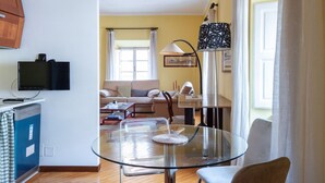 Ein modernes Wohnzimmer mit Glastisch, Sofa, Fernseher und Lampe.