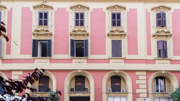 Ein pinkfarbenes Gebäude mit zahlreichen Fenstern und Balkonen.