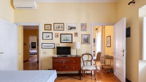 Ein Schlafzimmer mit Bett, Kommode, Stuhl und Wandfernseher.