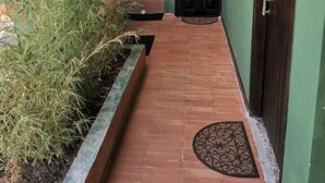 A corridor with a tiled floor, a black door, and a green wall. - La Bonita Guesthouse  (Bucaramanga)