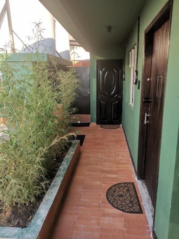 A corridor with a tiled floor, a black door, and a green wall. - La Bonita Guesthouse  (Bucaramanga)