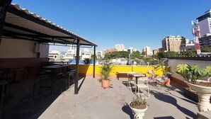 A rooftop terrace with outdoor seating, potted plants, and a view of the city skyline. - La Bonita Guesthouse  (Bucaramanga)