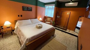 A bedroom with a bed, bedside lamps, a window, and a wardrobe. - La Bonita Guesthouse  (Bucaramanga)