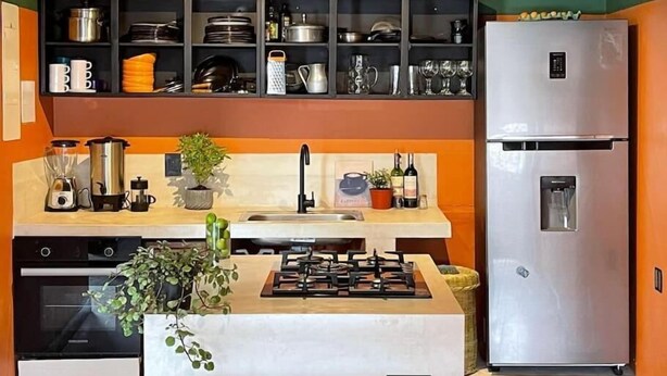 A modern kitchen with a gas stove, stainless steel refrigerator, and various kitchen utensils on shelves. - La Bonita Guesthouse  (Bucaramanga)