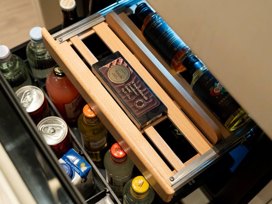 Un cajón con varias botellas y latas, incluyendo una botella de Laiba y una caja de galletas de chocolate.