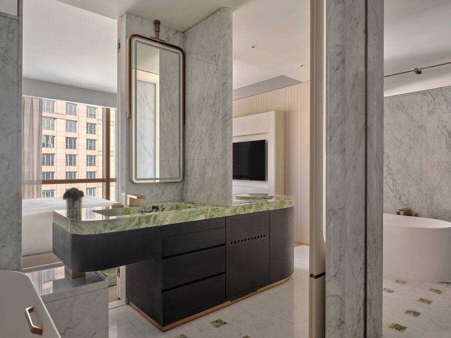 A modern bathroom with a marble vanity, a large mirror, and a bathtub.