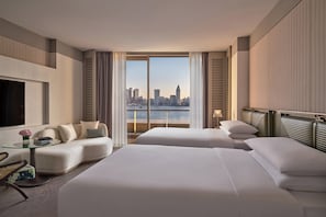 A hotel room with two beds, a sofa, a TV, and a view of a city skyline. - Regent Shanghai On The Bund (Shanghai)