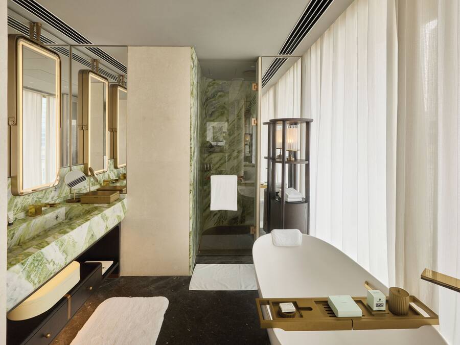 A modern bathroom with a marble vanity, a large mirror, a bathtub, and a glass shower enclosure.