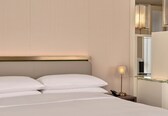 A hotel room with a bed, a nightstand, a lamp, and a mirror.