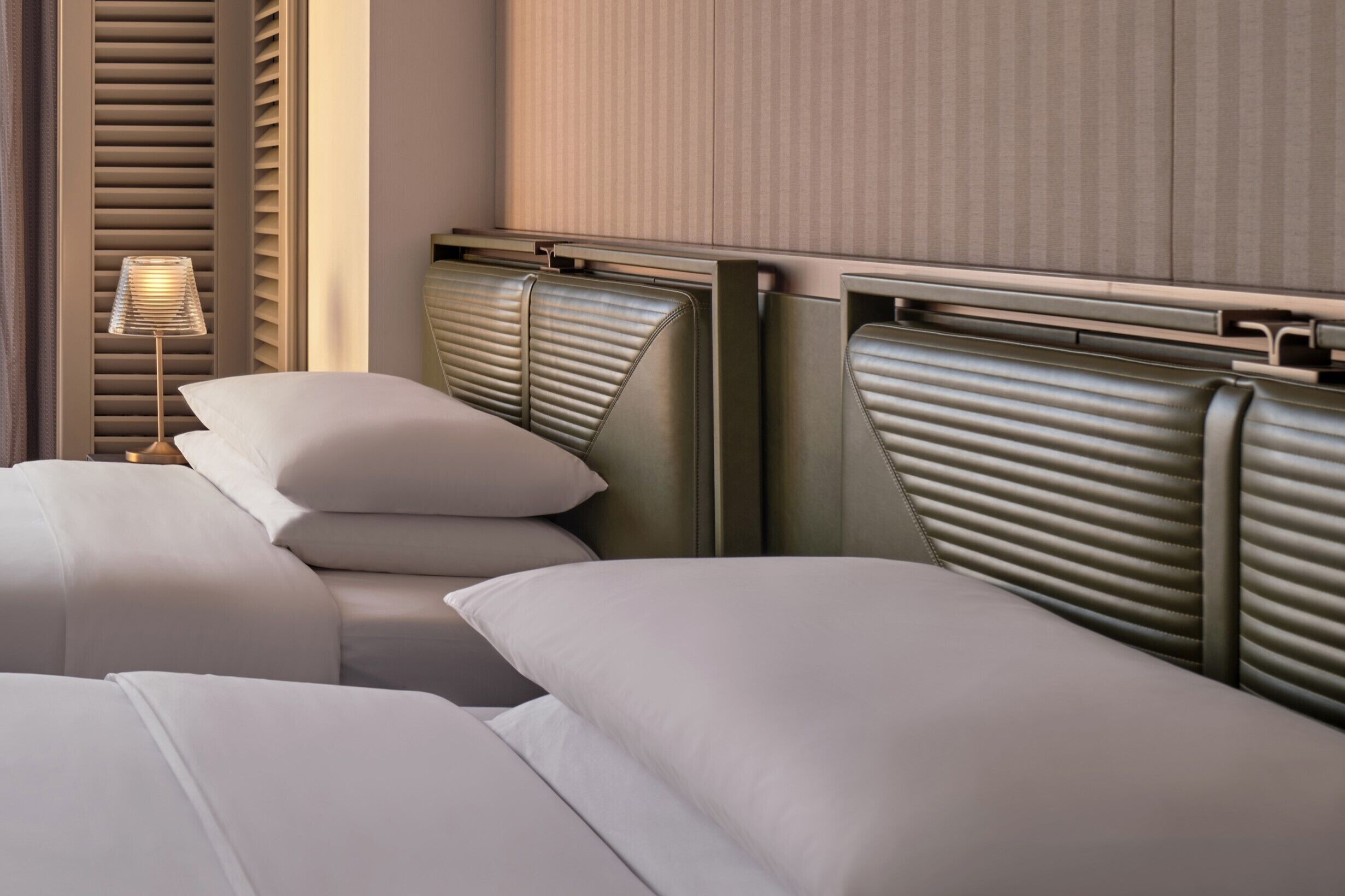 A hotel room with a bed, a nightstand, and a lamp.