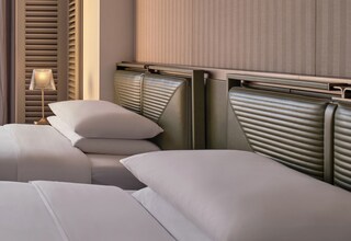 A hotel room with a bed, a nightstand, and a lamp.