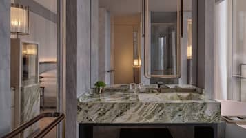 Une salle de bain moderne avec un comptoir en marbre, un grand miroir et une cabine de douche en verre.