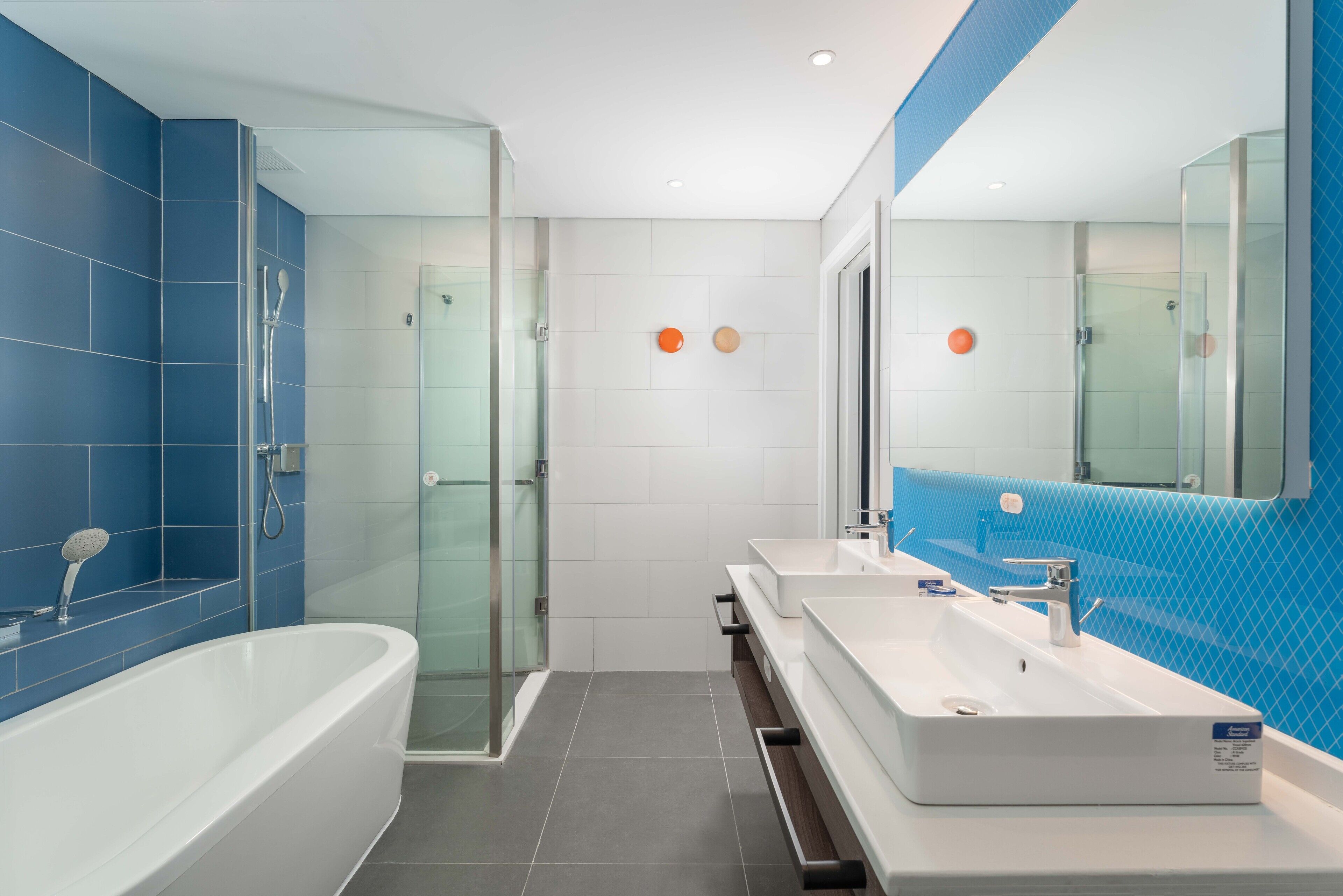 A modern bathroom with a glass-enclosed shower, a freestanding bathtub, and a vanity with a large mirror.