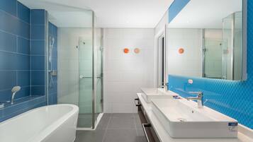 A modern bathroom with a glass-enclosed shower, a freestanding bathtub, and a vanity with a large mirror.