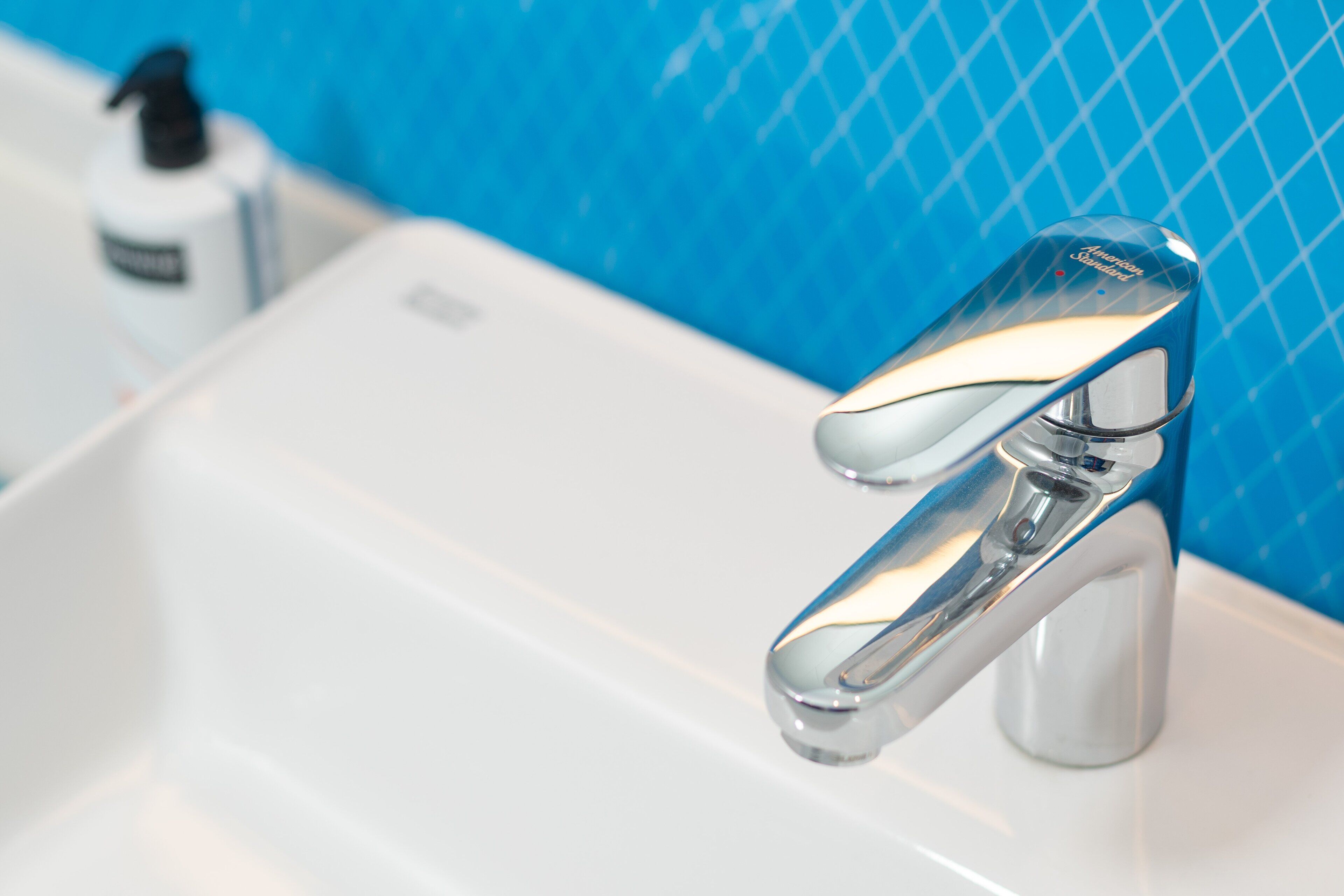 A bathroom sink with a chrome faucet and a bottle of hand soap.
