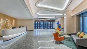 A modern lobby with a reception desk, seating area, and glass doors leading to other areas.
