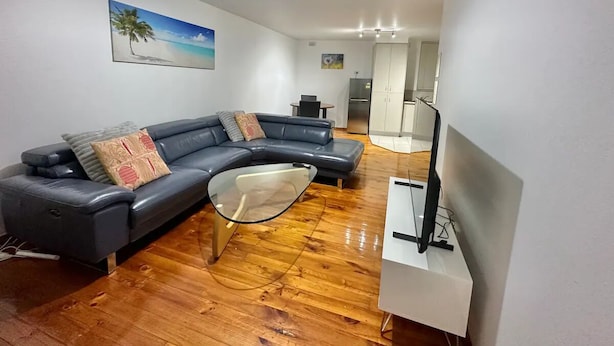 Una sala de estar moderna con un sofá modular, una mesa de centro de vidrio y un televisor de pantalla plana.