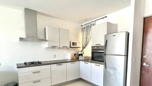 Une cuisine moderne avec des meubles blancs, des appareils en acier inoxydable et un sol carrelé.