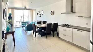 Une cuisine moderne avec des meubles blancs, une cuisinière à gaz et un coin repas comprenant une table et des chaises.