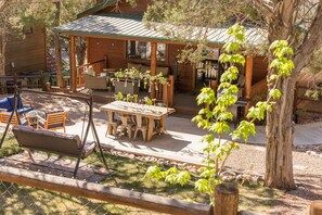 A wooden cabin with a covered patio, outdoor seating, and a swing set. - The Cabbage in Bison Ridge is minutes away from dining, hiking, and snow skiing. (Show Low)