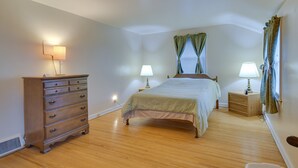 A bedroom with a wooden dresser, a bed with a green bedspread, two bedside lamps, and a window with curtains. - Convenient, Pet-Friendly Rochester Vacation Rental (Rochester)