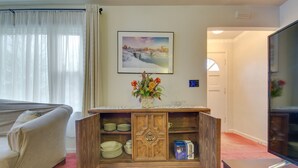 A living room with a sofa, a wooden cabinet with dishes, a framed picture on the wall, and a television. - Convenient, Pet-Friendly Rochester Vacation Rental (Rochester)