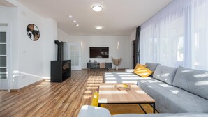 En moderne stue med sofa, sofabord, fjernsyn og pejs.