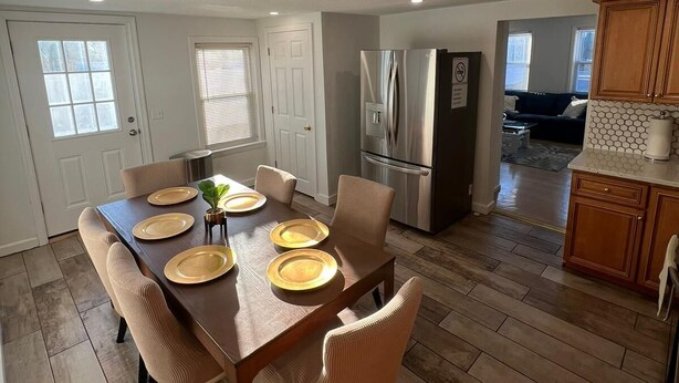 Un comedor amplio con una mesa de madera dispuesta para cuatro personas, rodeada de sillas con cojines.