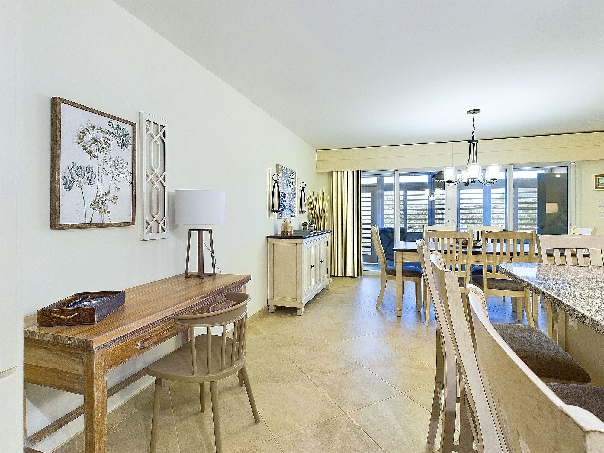 Un'ampia sala da pranzo con un tavolo e sedie in legno, una lampada e opere d'arte alle pareti.