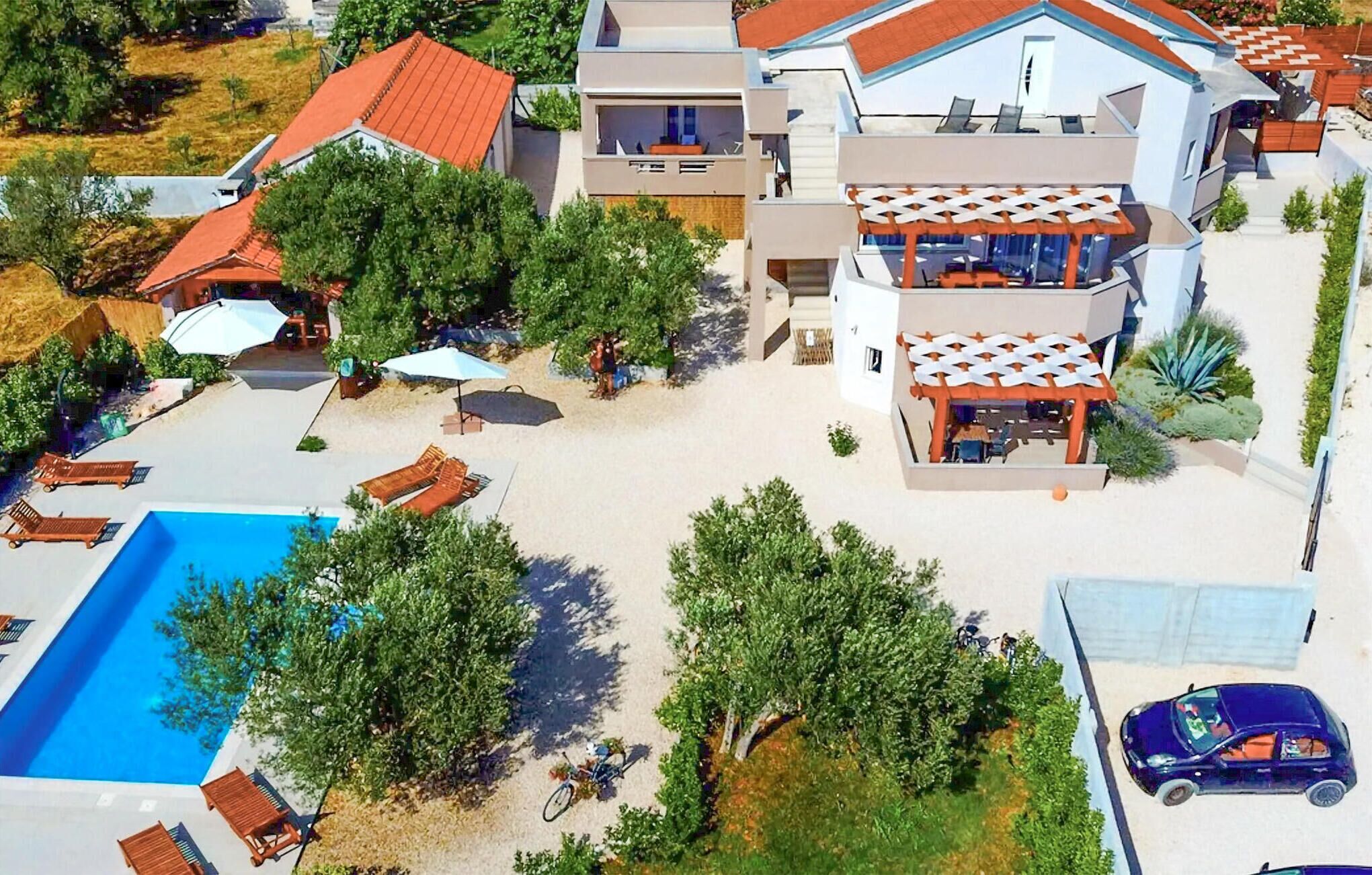 Uma casa moderna de dois andares com piscina, área de estar externa e um carro estacionado por perto.